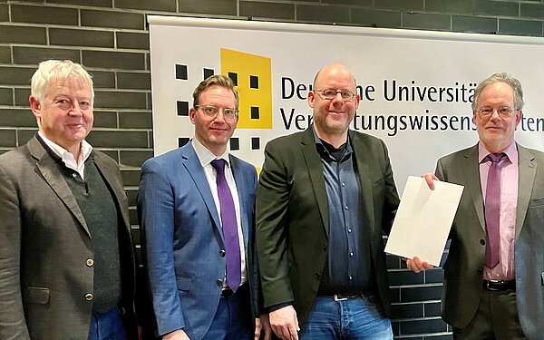 Stephan Bartholmei übergibt Bescheid an Rektor Univ.-Prof. Dr. Mühlenkamp
